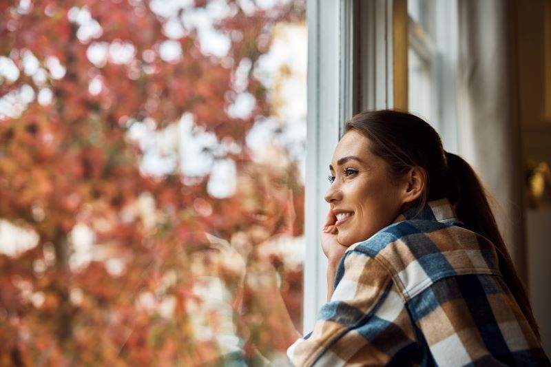 Smiling woman enjoying the view from her apartment